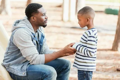 Parent/caregiver crouching down and holding a child's hands